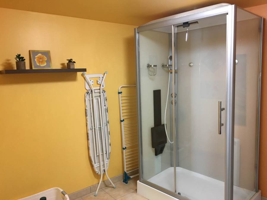salle d'eau avec grande cabine de douche, table à repasser et séchoir colonne